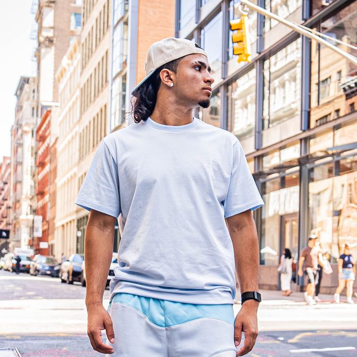Man wearing a light blue t-shirt and white cap on a city street