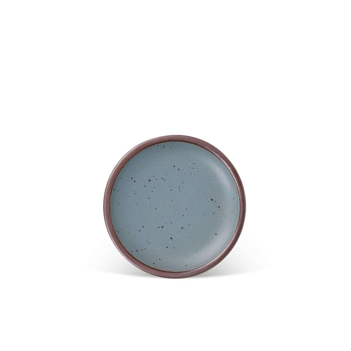 A dessert sized ceramic plate in a blue-grey color featuring iron speckles and an unglazed rim
