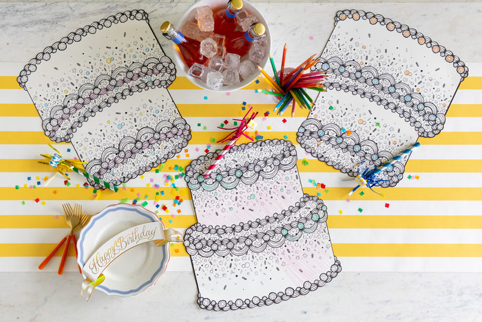 Die-cut Coloring Birthday Cake Placemats on a table with coloring pencils, confetti and an ice bucket of bottled drinks on the Marigold Classic Stripe Runner.