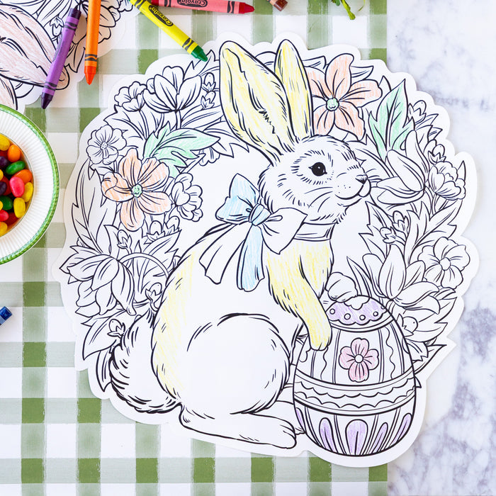 Die-cut Coloring Bunny Wreath Placemat partially colored in on a table with crayons and jelly beans.