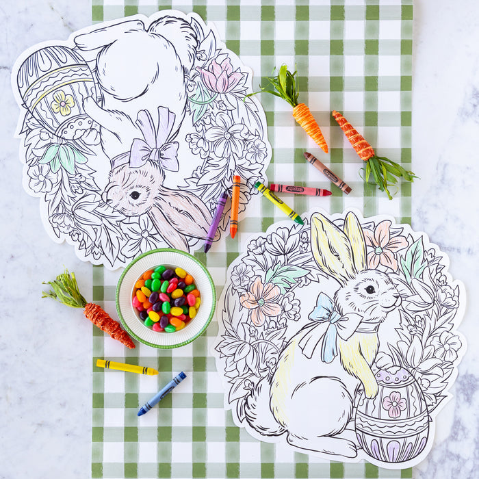 A table with Die-cut Coloring Bunny Wreath Placemats, bowl of jelly beans, crayons and carrots.