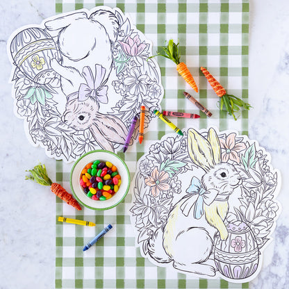 A table with Die-cut Coloring Bunny Wreath Placemats, bowl of jelly beans, crayons and carrots.