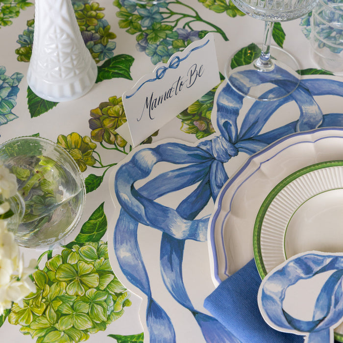 Elegant table setting with the Heirloom Blue Bow Place Card behind a place setting coordinating Heirloom Blue Bow products on the Hydrangea Runner.