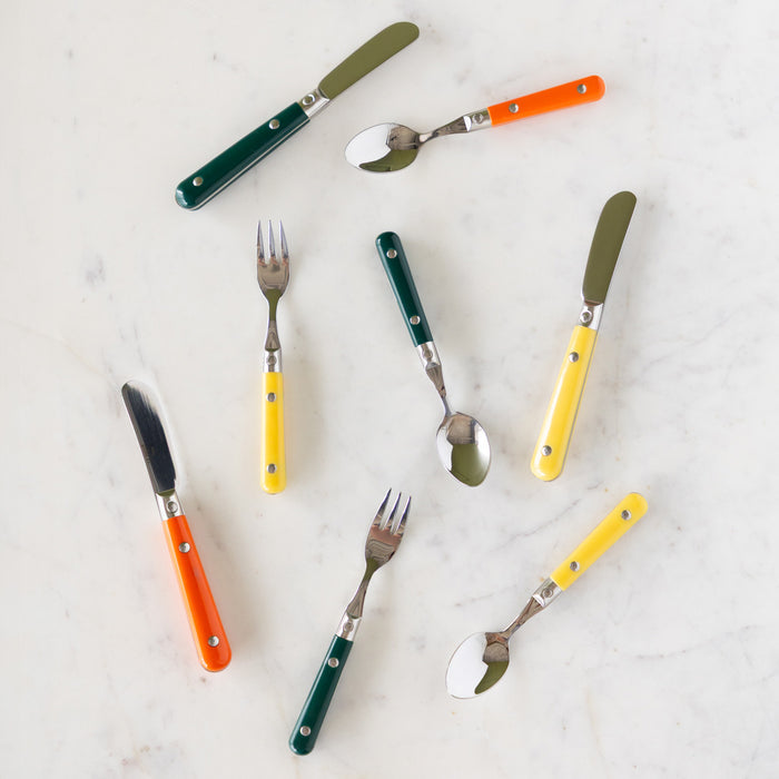 LePrix Cutlery utensils in dark green, orange and yellow scattered on a table.