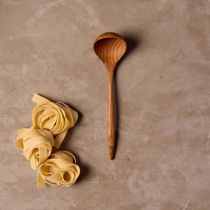 Teak sauce ladle on table with pasta