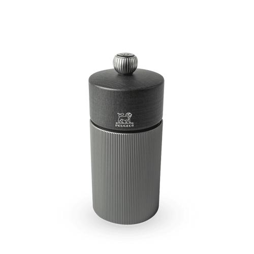 A dark carbon colored Peugeot pepper mill with elegant striations and a wood top.